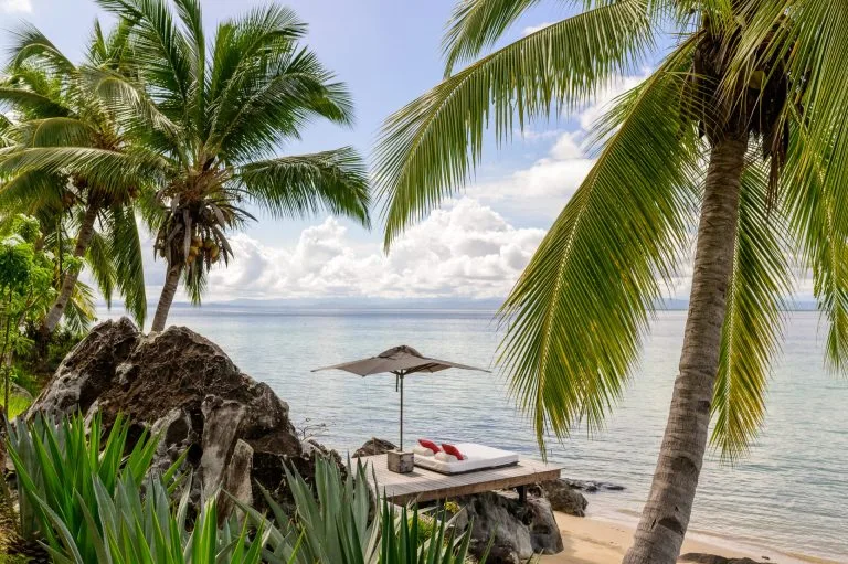 Plage bordée de cocotiers et transat face au lagon, Nosy Be