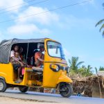Tuk-tuk jaune sur une route bordée de cocotiers à Tuléar
